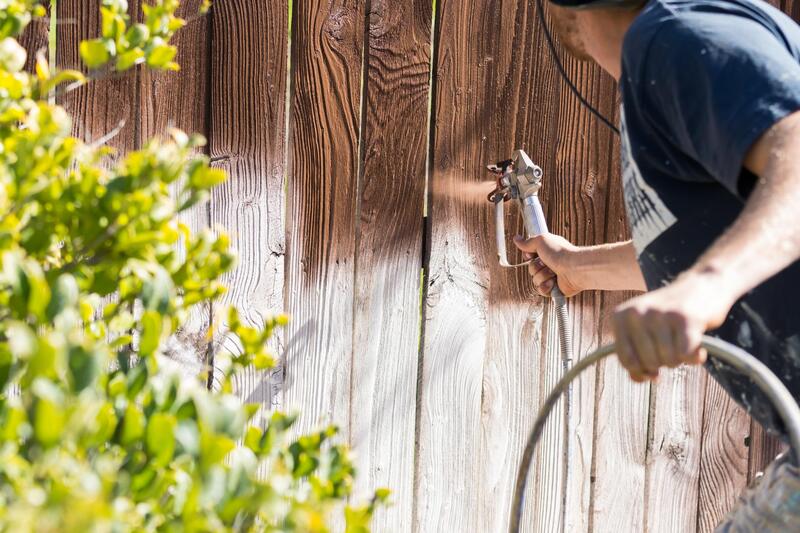 man spray painting a fence